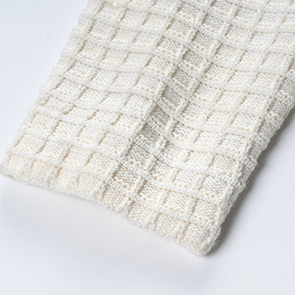 Textured white knitted jacket with black trim and decorative buttons paired with a ruffled hem skirt