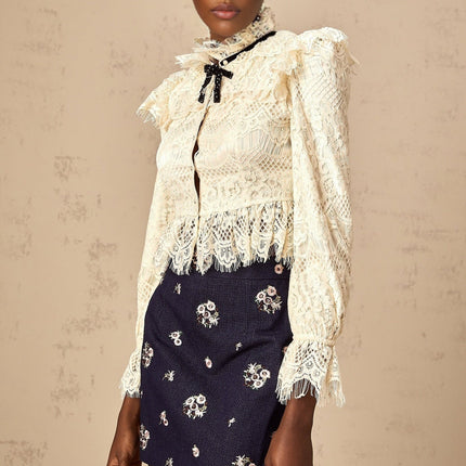 White blouse with floral lace pattern and bow detail at neckline