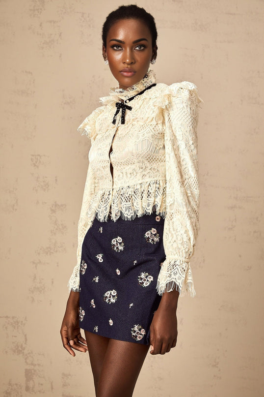 White blouse with floral lace pattern and bow detail at neckline