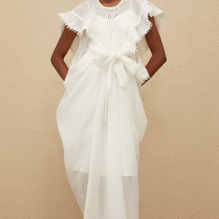 White cotton maxi dress with cap sleeves, tied waist, floral embroidery, and scalloped trim