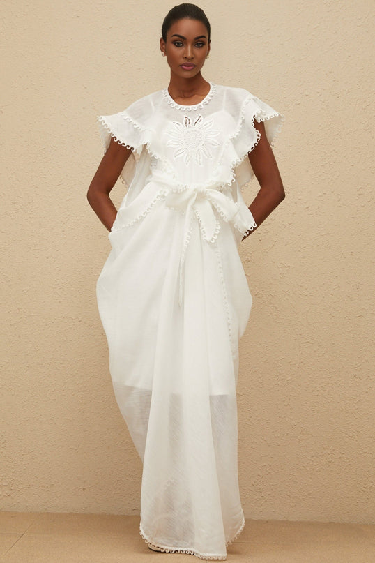 White cotton maxi dress with cap sleeves, tied waist, floral embroidery, and scalloped trim