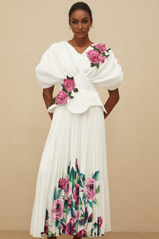 White V-neck batwing sleeve floral embroidered top with shirred effect and rear zip fastening, curved hem. White high rise pleated skirt with rose print, maxi length.