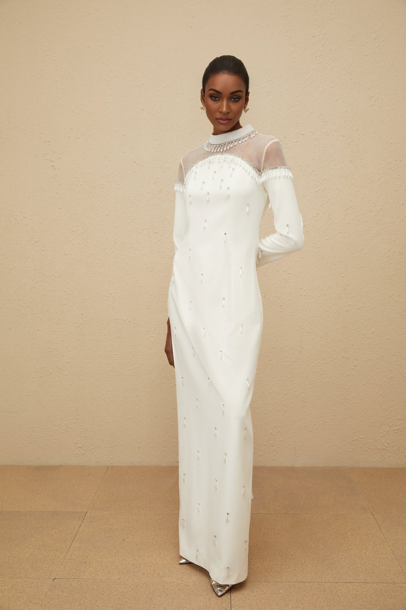 White long sleeve maxi dress with cinched waist, tulle panelling, faux-pearl and rhinestone embellishment, rear slit, and rear zip fastening