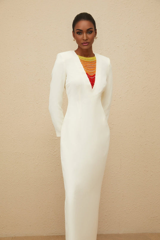 White maxi dress with bead and rhinestone embellishment, round neck, long sleeves, fitted waistline, rear slit, and rear zip fastening