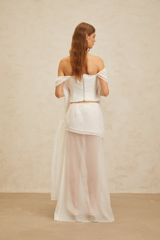 White off the shoulder tulle top with twisted knot and asymmetrical design, paired with high rise tulle skirt with draped detailing