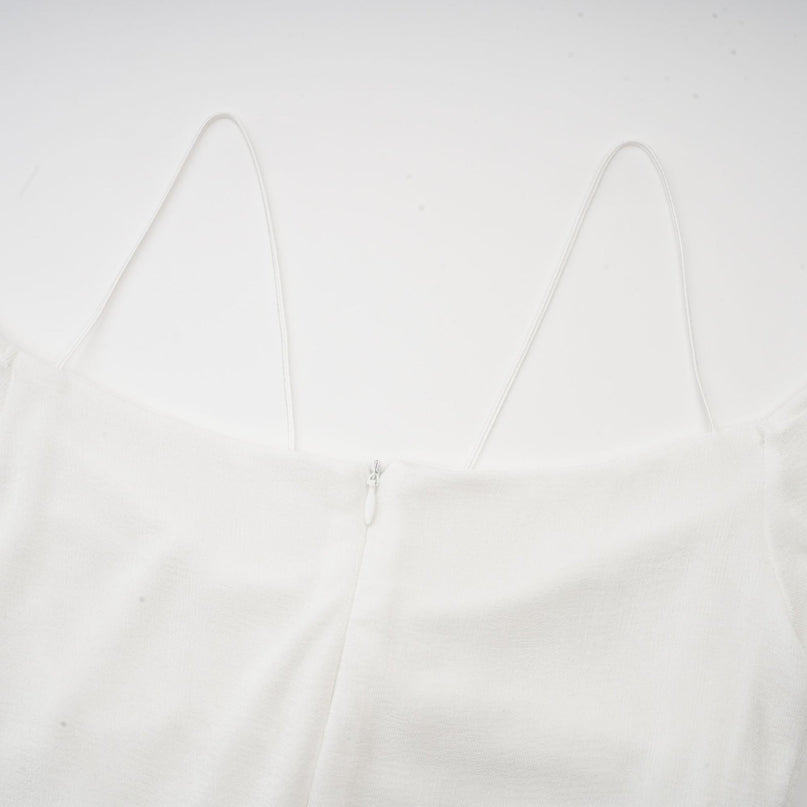 White offshoulder maxi dress with panelled design worn by a model standing against a plain background