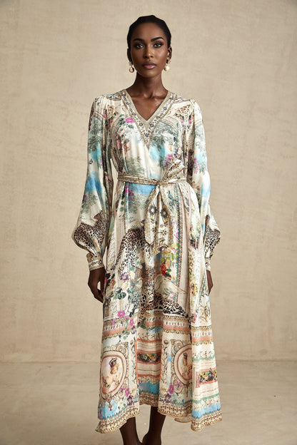 Woman wearing a belted midi dress with Vneck in flowing fabric standing against plain background