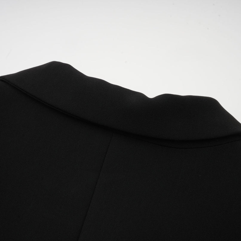 Woman wearing a black blazer dress with single button closure and fitted silhouette