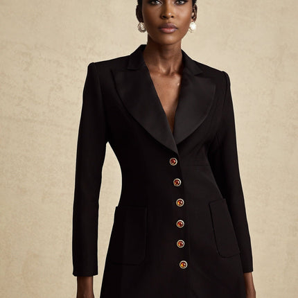 Woman wearing a black blazer dress with single button closure and tailored fit