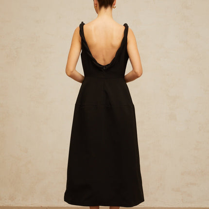 Woman wearing a black braided puff sleeve midi dress with a fitted waist and flared skirt