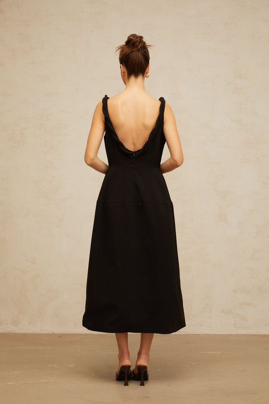 Woman wearing a black braided puff sleeve midi dress with a fitted waist and flared skirt