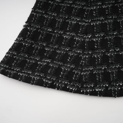 Woman wearing a black checked tweed matching set consisting of a sleeveless vest top and skirt with a plaid pattern