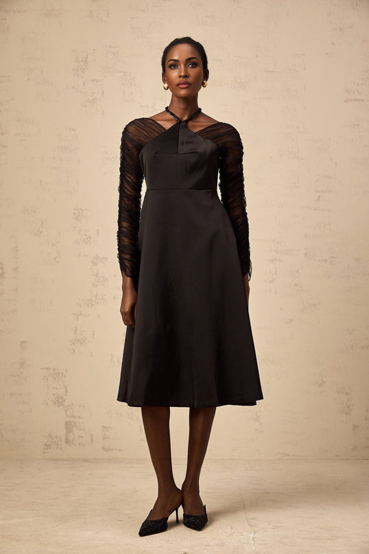 Woman wearing a black halterneck midi dress with panel detailing form fitting silhouette and sleek design