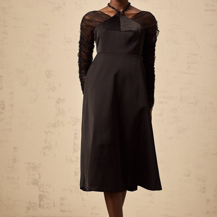 Woman wearing a black halterneck midi dress with panelled design standing in a neutral pose