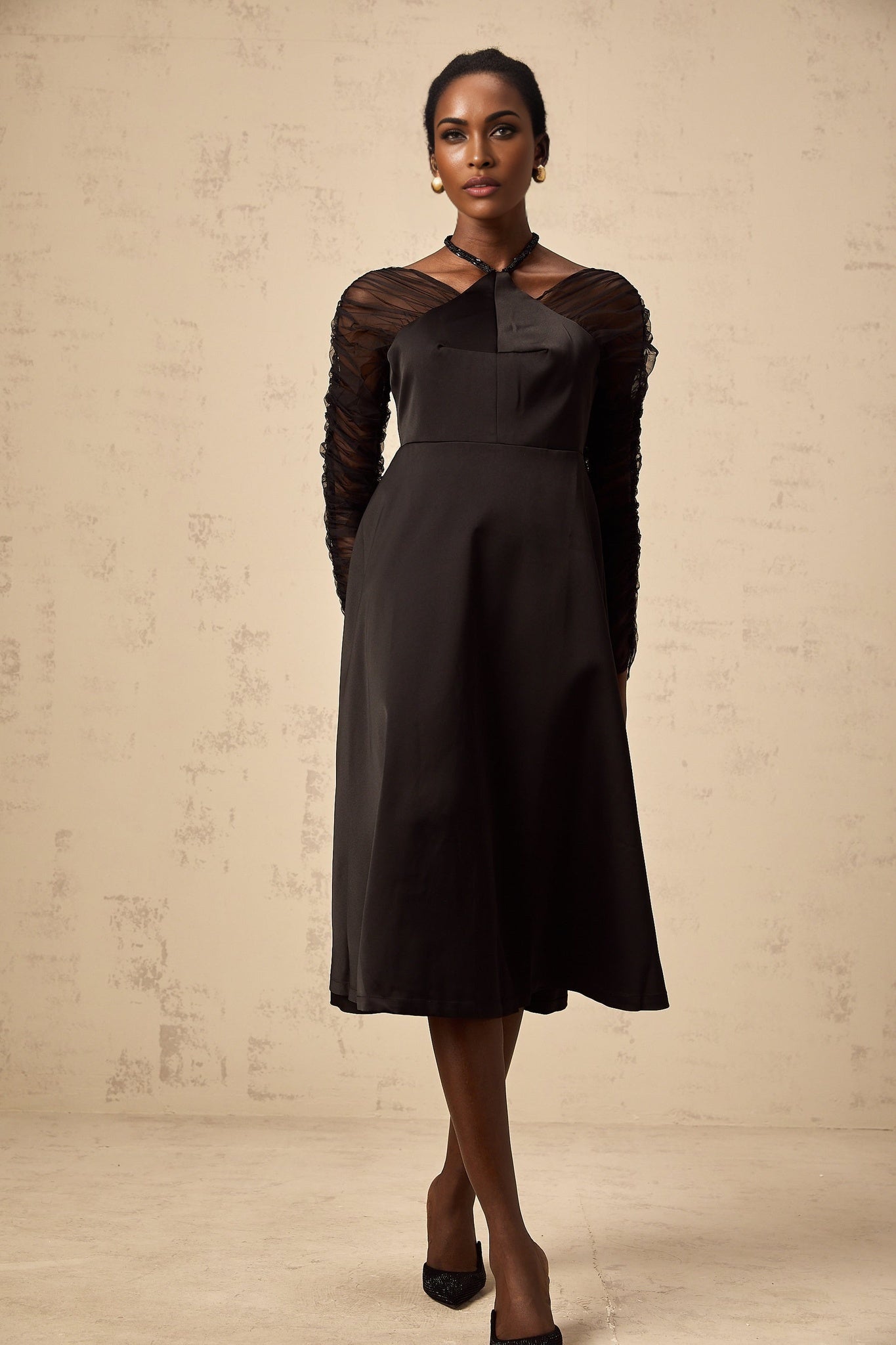 Woman wearing a black halterneck midi dress with panelled design standing in a neutral pose