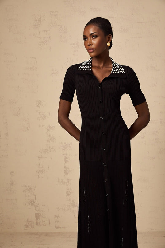 Woman wearing a black knit midi dress with studs on a plain background