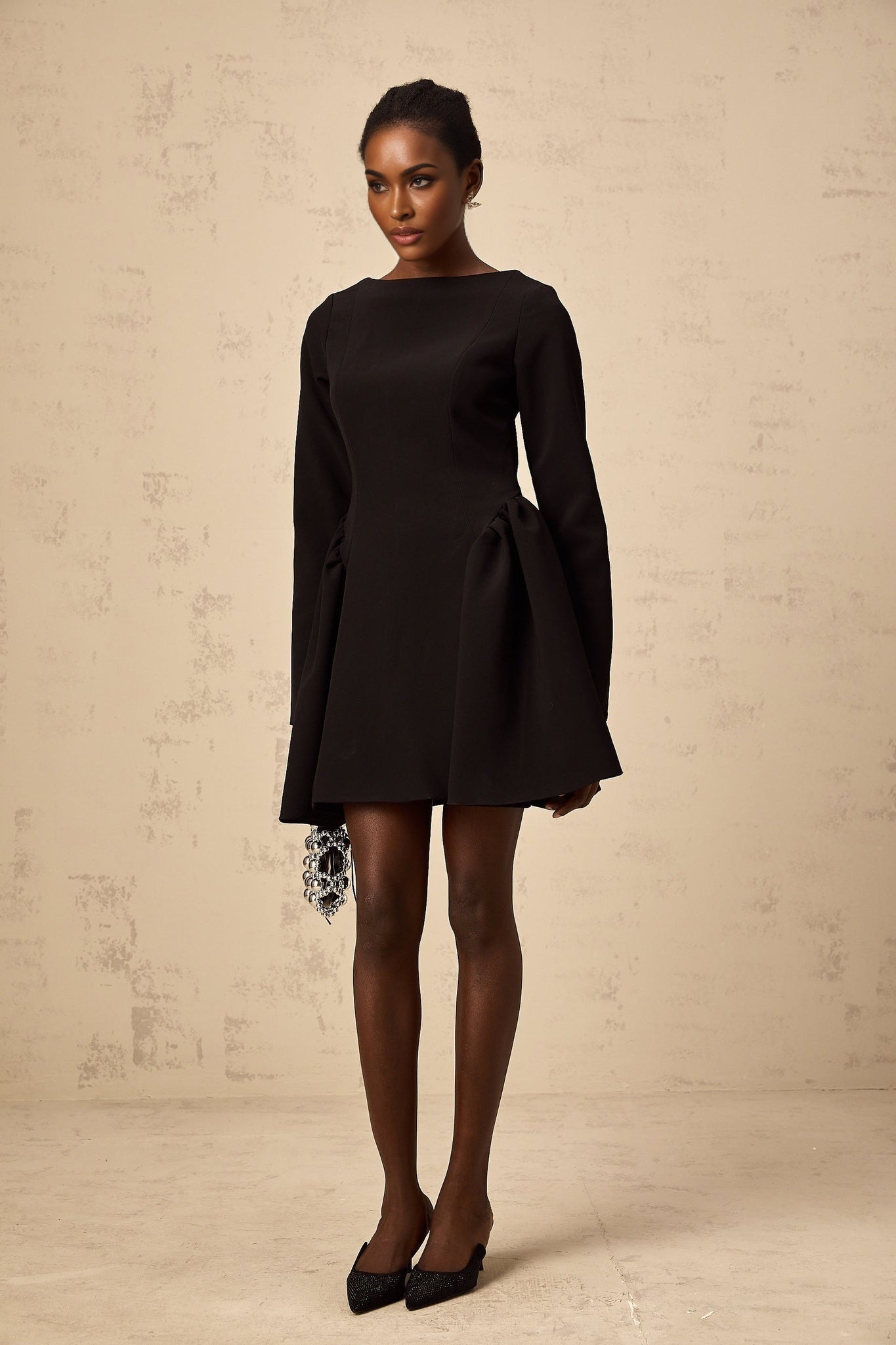 Woman wearing a black longsleeve mini dress with a flared skirt