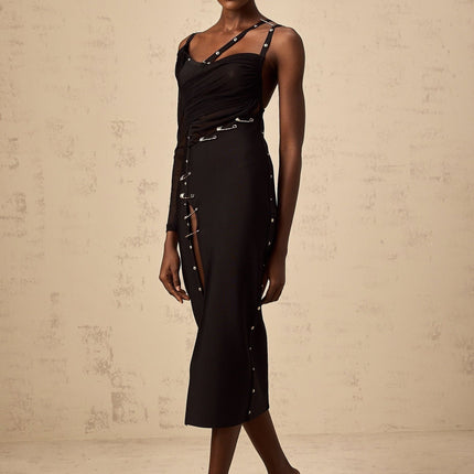 Woman wearing a black midi dress with asymmetric hemline and cut out details