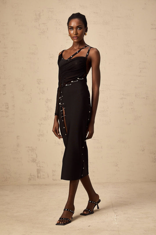 Woman wearing a black midi dress with asymmetric hemline and cut out details