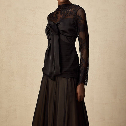 Woman wearing a black midi dress with floral lace panels and sheer details