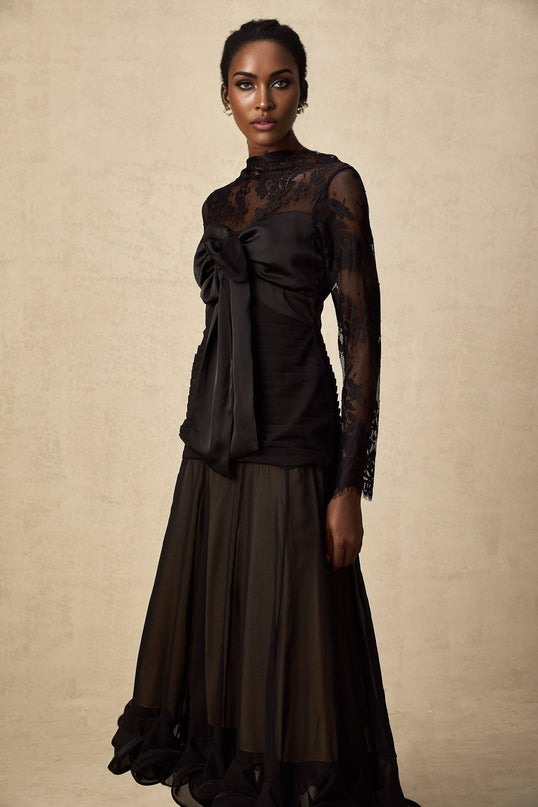 Woman wearing a black midi dress with floral lace panels and sheer details