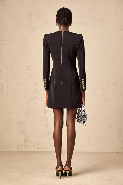 Woman wearing a black mini dress with lion head embellishments on the blazer style top