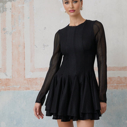 Woman wearing a black mini dress with puff sleeves and pointelle knit pattern