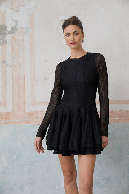 Woman wearing a black mini dress with puff sleeves and pointelle knit pattern