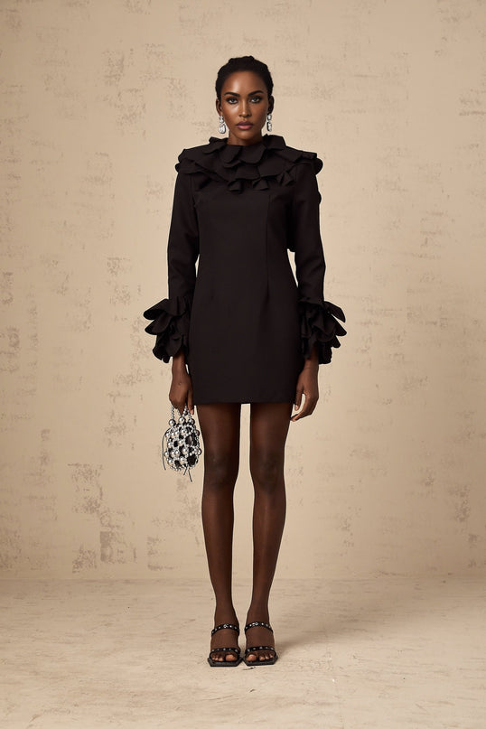 Woman wearing a black mini dress with ruffled details and an open back design