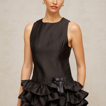 Woman wearing a black mini dress with ruffled tiers and a short hemline
