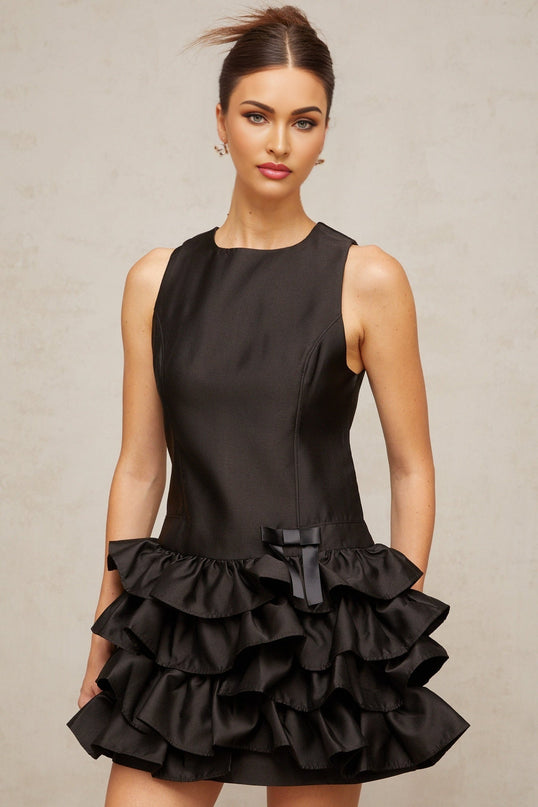 Woman wearing a black mini dress with ruffled tiers and a short hemline