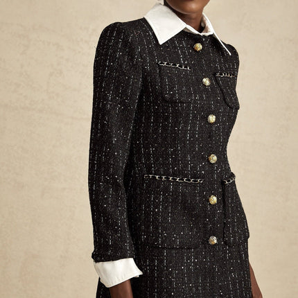 Woman wearing a black mini dress with sequin panels and tweed fabric combination form fitting silhouette short length sleeveless design