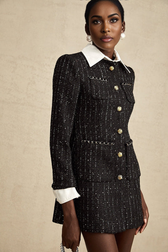 Woman wearing a black mini dress with sequin panels and tweed fabric combination form fitting silhouette short length sleeveless design