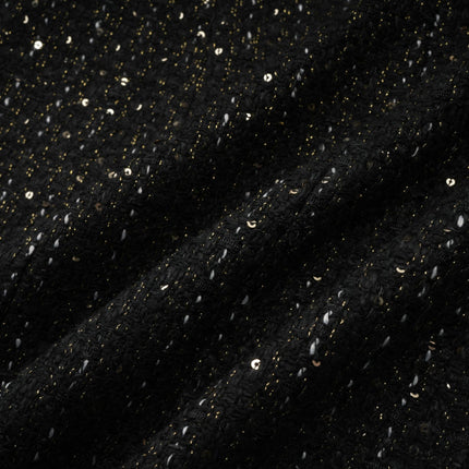 Woman wearing a black mini dress with sequin panels and tweed fabric combination sleeveless design form fitting silhouette