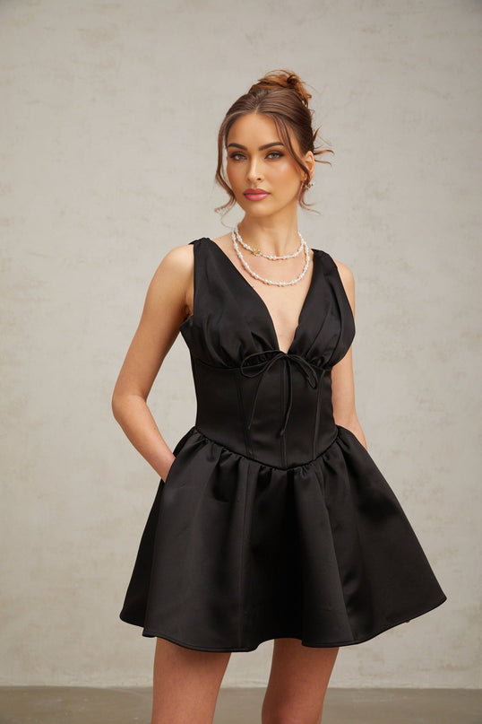 Woman wearing a black mini dress with Vneck and flared skirt