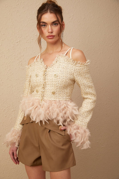Woman wearing a black off shoulder tweed top with white feather trim along the neckline and sleeves