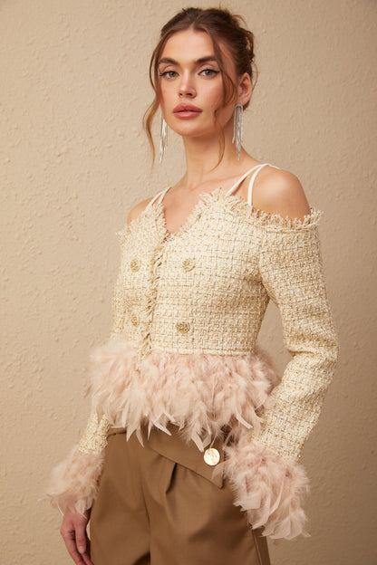 Woman wearing a black off shoulder tweed top with white feather trim along the neckline
