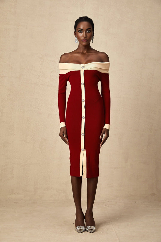 Woman wearing a black offshoulder knit midi dress with long sleeves standing against a plain background