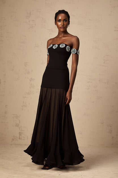 Woman wearing a black offshoulder top with embellishments named Carina