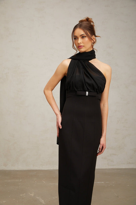 Woman wearing a black one shoulder midi dress with draped fabric details
