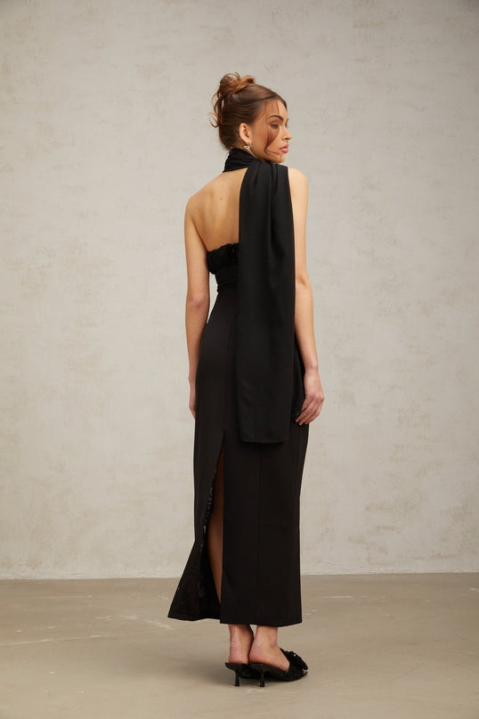 Woman wearing a black oneshoulder midi dress with draped fabric detail
