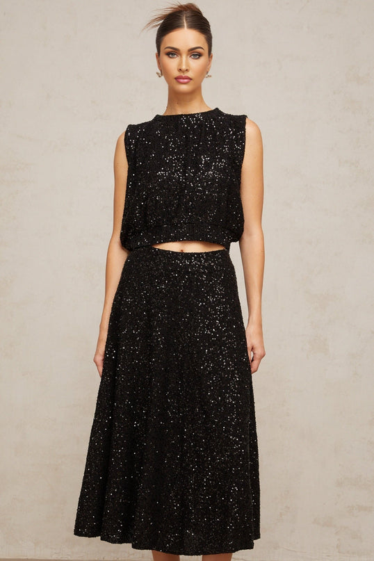 Woman wearing a black sequined knit vest and matching skirt set Ulrique brand outfit for evening wear