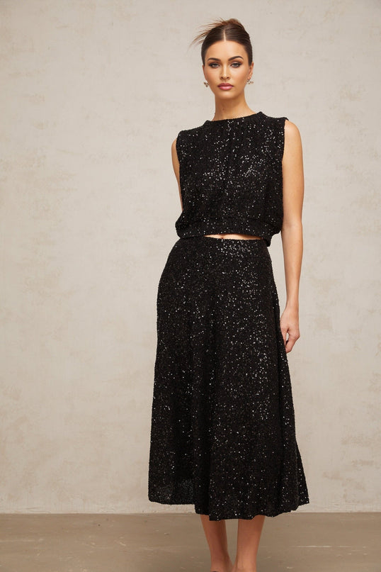 Woman wearing a black sequined knit vest and matching skirt set Ulrique design shimmering outfit for evening wear