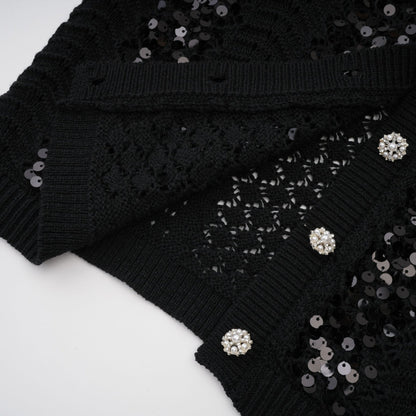 Woman wearing a black sequined matching set with crochet knit cardigan and skirt