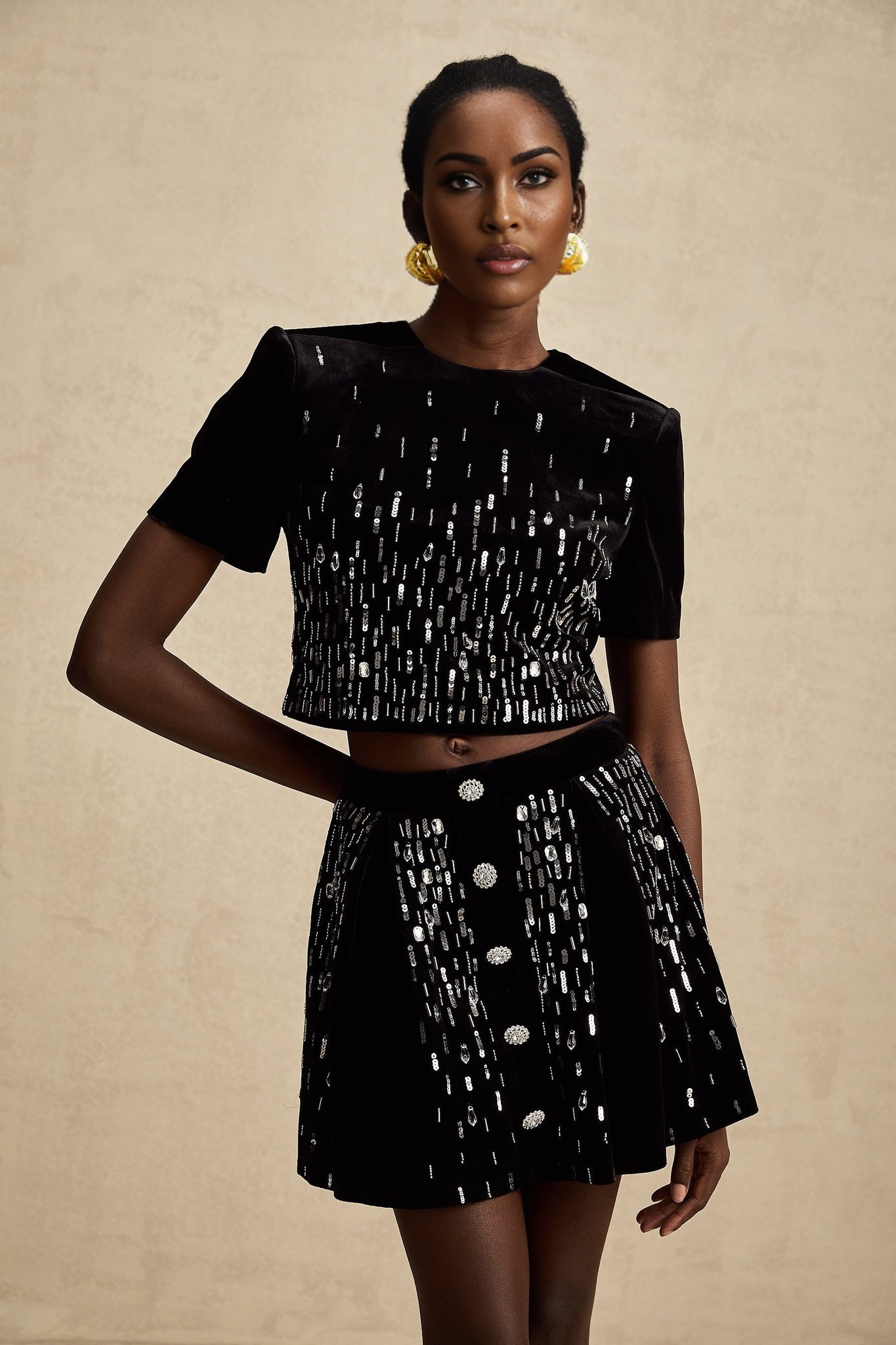 Woman wearing a black velvet matching set consisting of an embellished top and skirt named Isabeau