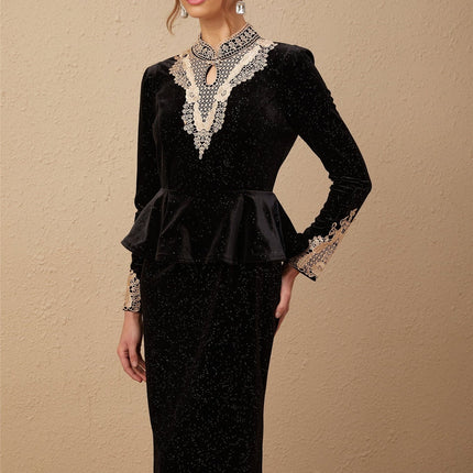 Woman wearing a black velvet midi dress with embellishments standing in a neutral pose