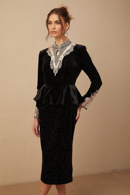 Woman wearing a black velvet midi dress with embellishments standing in a neutral pose