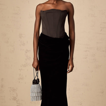 Woman wearing a black velvet offshoulder floorlength maxi dress with a sleek silhouette