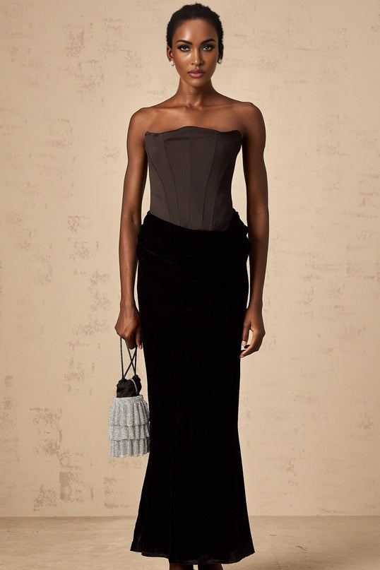 Woman wearing a black velvet offshoulder floorlength maxi dress with a sleek silhouette