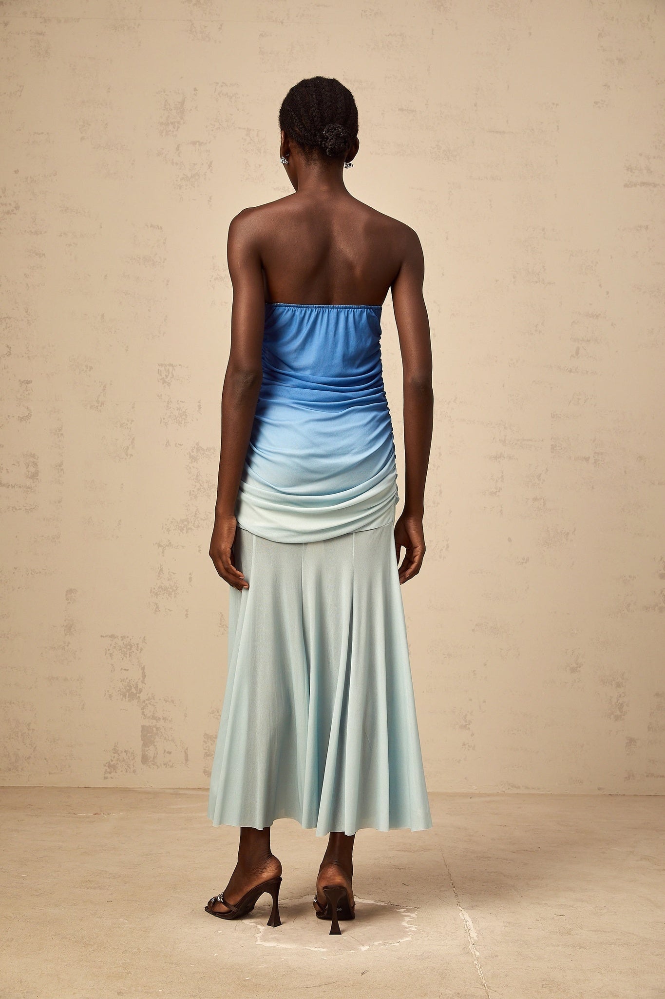 Woman wearing a blue gradient mesh midi dress with sheer fabric and ombre effect from light to dark blue